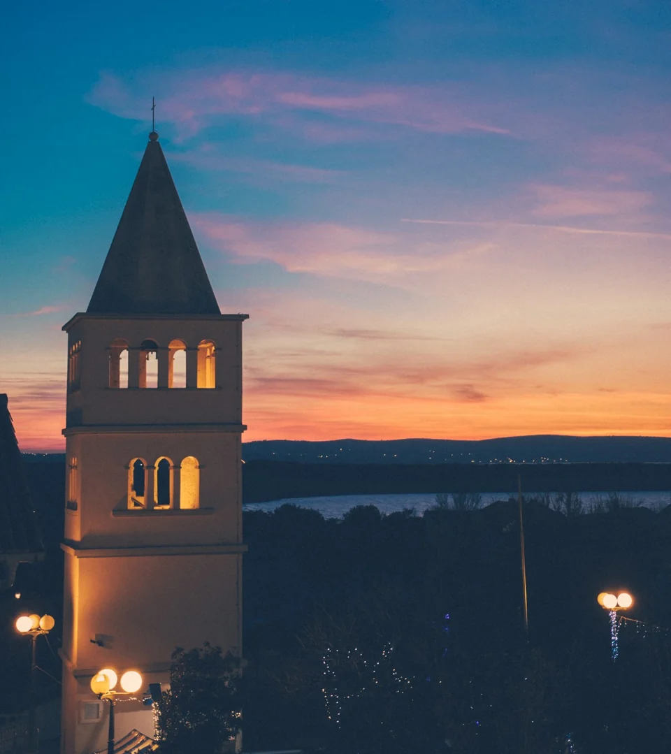 Kirchturm von Povljana vor dem warmen Himmel des Sonnenuntergangs